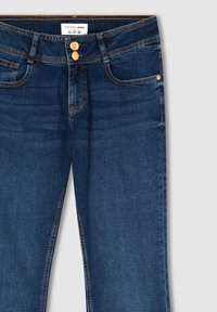 Ciemnoniebieskie dżinsy o klasycznym kroju, z zapięciem na guziki i złotymi detalami. Zawierają pięć kieszeni i dyskretne szwy.