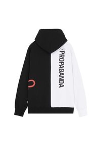 Hoodie met een gesplitst ontwerp; de ene kant zwart, de andere kant wit. Bevat "PROPAGANDA" in vette letters en een rode accenten. Gemaakt van katoen.