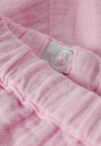 Tejido rosa con borde fruncido y un botón transparente, con detalles texturizados y tejidos en un material suave.