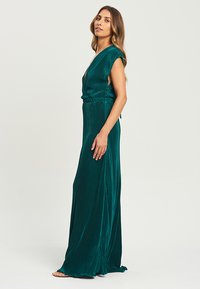 Robe maxi en vert foncé, en tissu texturé avec des plis verticaux, décolleté en V, manches courtes et taille élastique.