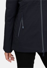 Veste imperméable marine dotée d'une poche zippée, d'un col montant, de poignets élastiques et d'une texture lisse. Le tissu a une finition mate.