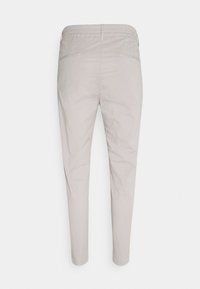 Pantaloni beige chiaro a gamba stretta con una cintura elastica, dotati di due tasche posteriori e una texture liscia e opaca.