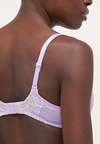 Lavendel blonde bh med mesh bak. Justerbare stropper og krok- og øye-lukking. Har broderte blomsterdetaljer for en intricert tekstur.