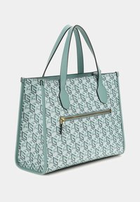 Jasnozielona torba na ramię z geometrycznym wzorem, dwoma górnymi uchwytami oraz przednią kieszenią na zamek błyskawiczny z złotym suwakiem.