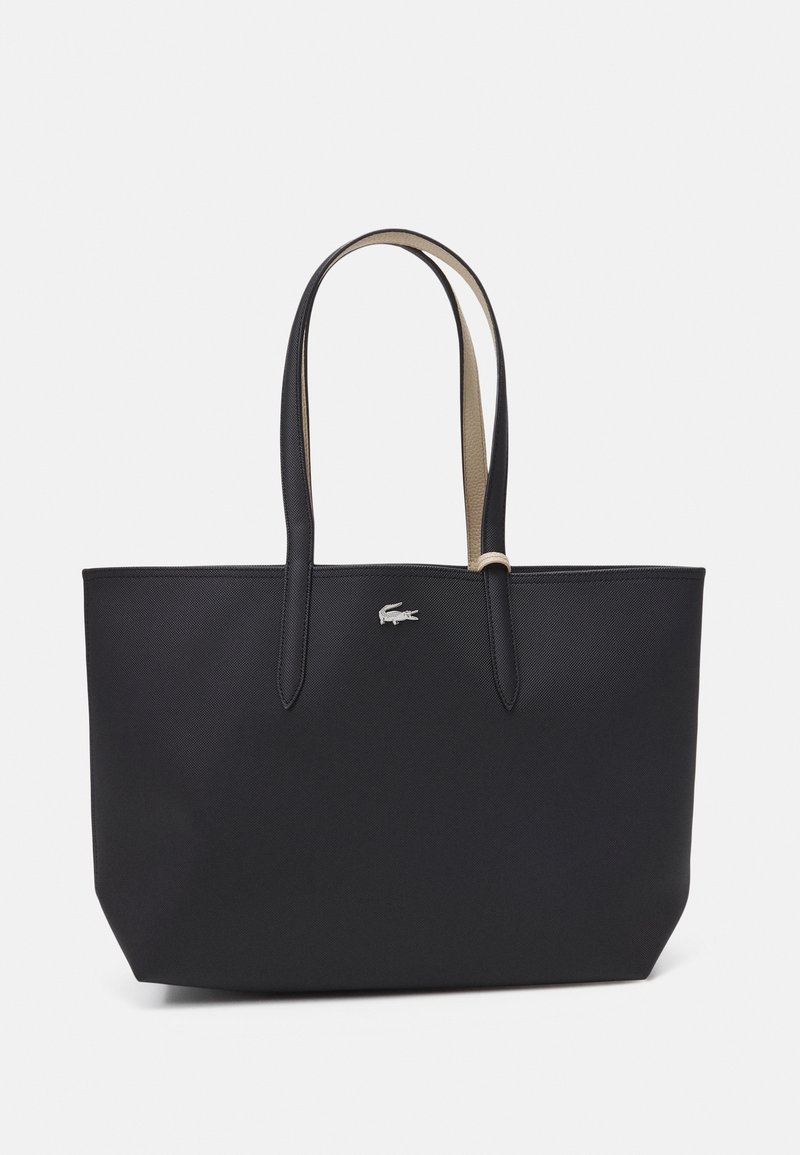 Sac cabas noir avec deux longues anses et un petit logo crocodile argenté en haut au centre devant.