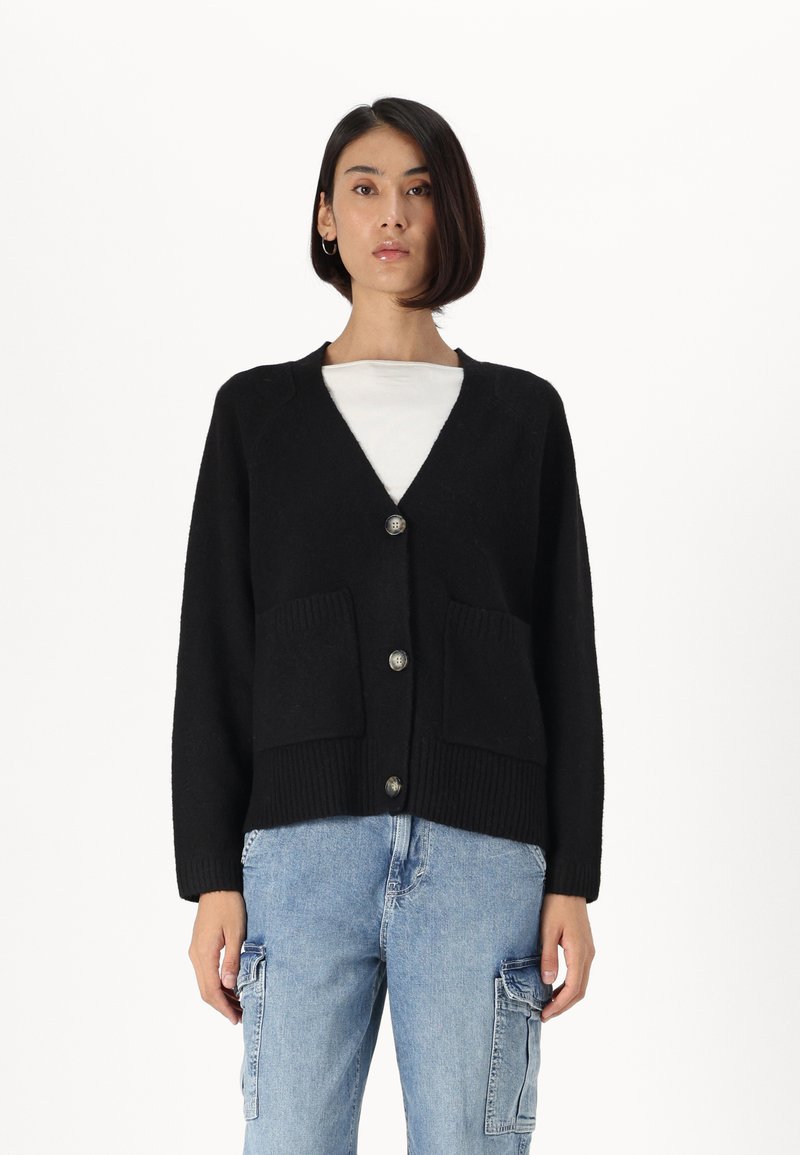 Cardigan nero con scollatura a V, dotato di due tasche frontali e bottoni argentati. Realizzato in un morbido tessuto texturizzato, con maniche a vestibilità ampia.