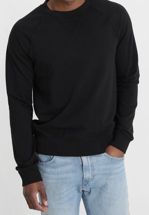 Sudadera negra de manga larga con cuello redondo y puños acanalados. Fabricada con material cómodo, presenta un diseño simple y limpio.
