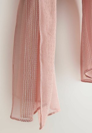 Hele roosa läbipaistev kangas vertikaalsete valgete õmmeldud joontega, mis ripub kahvatu tausta ees.