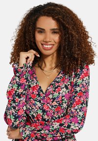 Blumenwickelkleid mit schwarzem Hintergrund, geschmückt mit pinken, roten und grünen Blumen; lange Ärmel mit gerafften Manschetten; V-Ausschnitt.