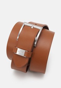 Ceinture en cuir marron avec une boucle en métal argenté. Elle présente une texture lisse et un logo subtil sur le fermoir. Ajustable avec plusieurs trous.