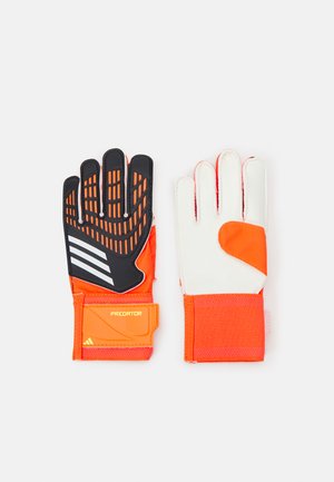 Guantes de portero en negro y naranja con agarre texturizado, acentos blancos y una muñequera de un naranja intenso. Cuenta con cierre de velcro ajustable.