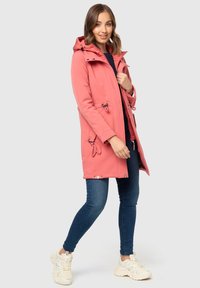 Light pink waterproof coat with adjustable hood, drawstring waist, two front pockets, and silver hardware accents, paired with blue jeans.