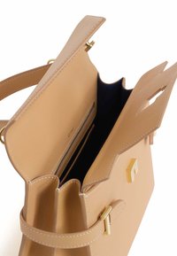 Bolso de mano de cuero tono marrón claro con un diseño estructurado, detalles en metal dorado y un bolsillo con cremallera en el interior. Presenta una abertura superior y un interior oscuro en contraste.