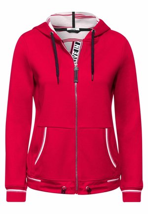 Sudadera roja con cremallera, forro de la capucha a rayas blancas y rojas, cordones negros, bolsillos delanteros y ribete blanco en los puños y bolsillos.