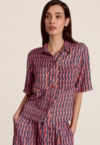 Kortebloesjes overhemd met knopen in marineblauw, rood en roze geometrisch patroon. Lichtgewicht stof, spread collar en één borstzak.
