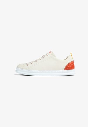 Niedrig geschnittene weiße Sneaker mit abgerundeter Zehenpartie, weißen Schnürsenkeln mit roten Sprenkeln, rotem Fersenpatch mit Zickzacknähten und weißer Sohle.
