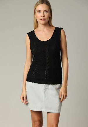 Top en tricot noir avec un décolleté en forme de vague et un motif ondulé ; associé à une jupe en denim gris clair.