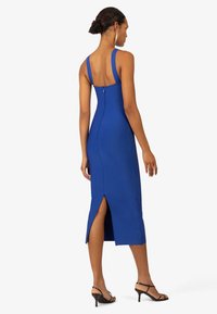 Robe sans manches bleue au design ajusté, avec une fente sur le côté et une fermeture éclair à l'arrière. Tissu lisse avec une silhouette longueur genou.