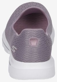 Lila nät-sneaker utan snörning med en texturerad yta, vit sula och en liten rund logotypdetalj på hälen. Lätt och andningsbar design.