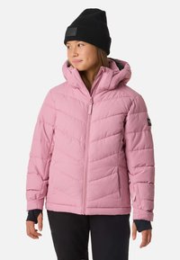 Lyserød isoleret jakke med hætte og chevron-syning, med foran lynlås og sorte accenter. Båret over en mørk skjorte.