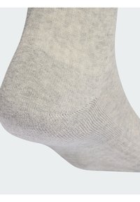 Calcetín gris claro con textura de punto suave y talón y puntera reforzados. El diseño es sin costuras y ofrece un ajuste cómodo alrededor del tobillo.