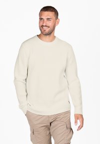Hellbeige strukturierter Pullover mit Rundhalsausschnitt und langen Ärmeln. Kombiniert mit beigen Cargo-Hosen, die eine entspannte Passform zeigen.