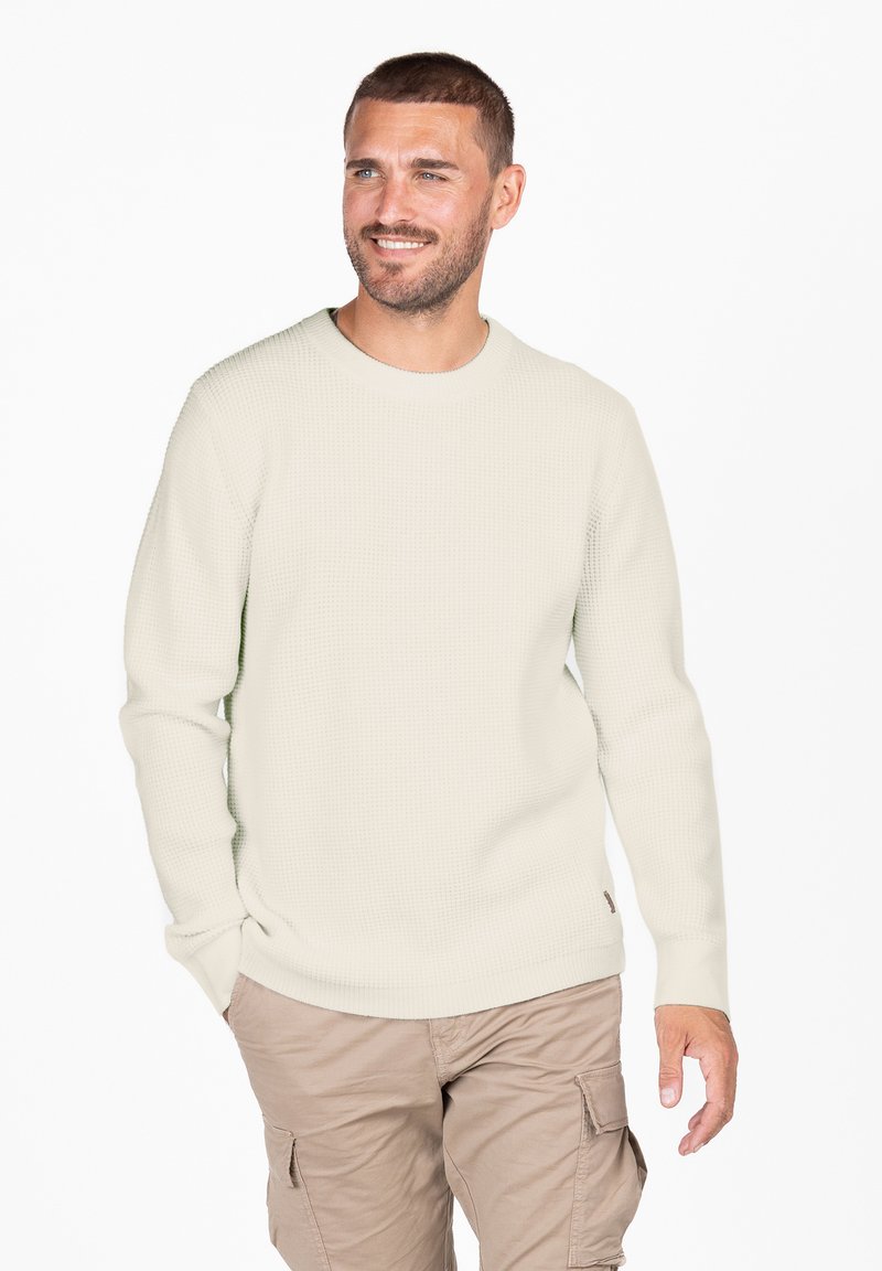 Hellbeige strukturierter Pullover mit Rundhalsausschnitt und langen Ärmeln. Kombiniert mit beigen Cargo-Hosen, die eine entspannte Passform zeigen.