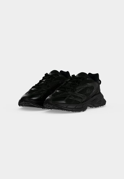 Paire de baskets noires de sport avec détails en mesh et cuir, semelles épaisses et lacets sur fond blanc.