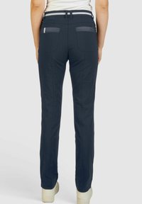 Pantalon bleu marine au design ajusté, avec deux poches arrière et une taille rayée blanche contrastante. Fabriqué à partir d'un tissu lisse.