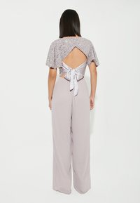 Jumpsuit viola chiaro con top a maniche corte di paillettes e schiena scoperta, dotato di chiusura con fiocco in satin e pantaloni a gamba larga.