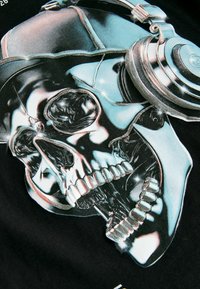 Grafiska T-krekls ar metāliskiem skeleta motīviem, kas nēsā austiņas, uz melna fona. Skeletam ir spīdīgi sudraba akcenti.