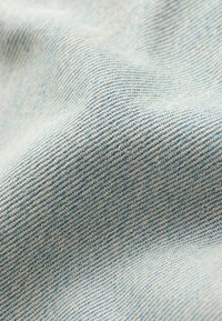 Helehelesin sinine denimpublik kangas, mis on kudumisega twill, pehme tekstuuriga ja kerge tuhmumisega, luues teatud kohtades kerge läike.