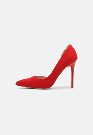 Escarpin rouge à talon haut avec bout pointu et talon aiguille fin, présenté sur fond blanc uni.