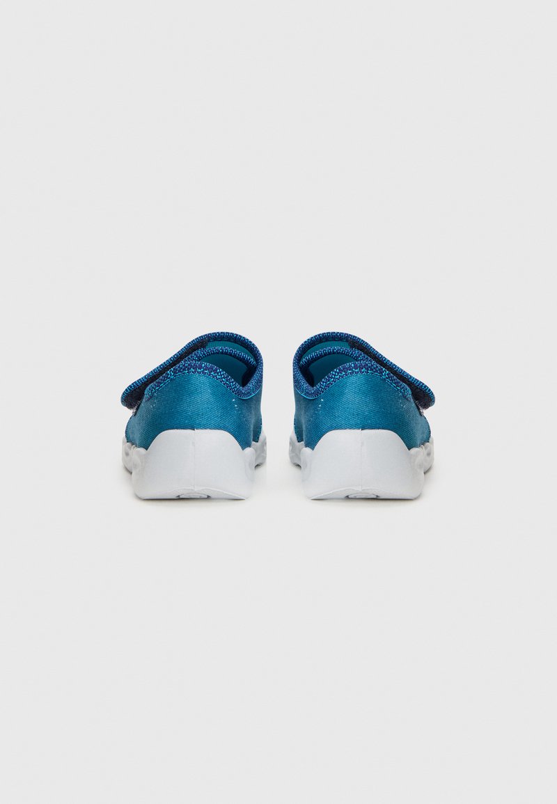 Helle blaue Stoff-Rutschschuhe mit strukturiertem Finish, runden weißen Sohlen und schrägem Rücken-Design. Verstellbarer Riemen an der Ferse.