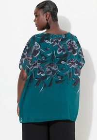 Turkise bluse med blomsterprint og korte ærmer, præget af sorte og grå blomster mønstre, letvægtsstof og løs pasform.