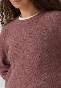 Rosenfarbener Strickpullover mit strukturierter Musterung, Rundhalsausschnitt und langen Ärmeln. Der Stoff wirkt weich und gemütlich.