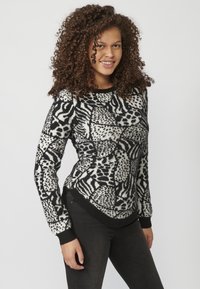 Czarny i biały sweter w wzory z okrągłym dekoltem, długimi rękawami oraz teksturowanym materiałem, prezentujący różne geometryczne wzory.