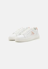 Sneakers bianchi in pelle con suola in gomma texturizzata. Le caratteristiche includono un logo sul lato, punta arrotondata e dettagli in colori pastello a contrasto sul tallone.