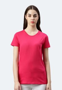 T-shirt a maniche corte di un vivace colore rosa, con colletto tondo e tessuto di cotone morbido, dal taglio aderente.