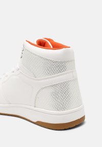 Vysoké tenisky z bílé syntetické kůže, s síťovinovými panely, oranžovým podšívkou a gumovou podrážkou. Texturovaný zadní díl pro lepší uchopení a podporu.