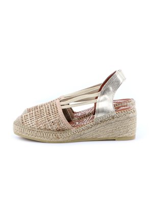 Sandalo espadrillas con zeppa, parte anteriore beige intrecciata, cinturino alla caviglia color argento metallizzato, fasce laterali elastiche e suola in juta intrecciata.