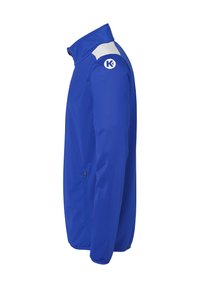 Blauwe softshell jack met een hoge kraag, witte accenten op de schouders en een ritssluiting zijzak. Bevat een logo op de arm.
