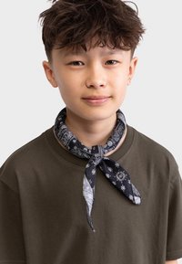 Schwarzes und graues Bandana Halstuch mit Paisley-Muster, vorne verknotet, getragen über einem olivgrünen T-Shirt mit Rundhalsausschnitt.