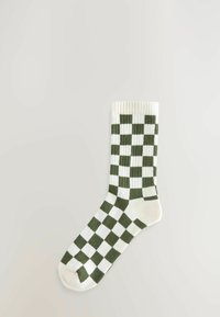 Calzino di cotone a quadri verdi e bianchi con bordo a costine; la texture è liscia e presenta motivi quadrati alternati su tutta la superficie.