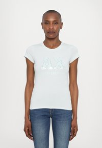 Šviesiai mėlynas medvilnės marškinėliai su trumpomis rankovėmis, su blizgučių "AX" logotipu ir "ARMANI EXCHANGE" tekstu po juo. Priglustanti dizaino.