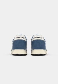 Blue suede sneakers with white accents, featuring a rounded shape, textured panels, and a rubber sole. "CONVERSE" is printed on the heel.