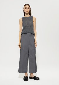 Gray knit sleeveless top with textured pattern, paired with wide-leg gray trousers and black flat sandals. Neutral background.