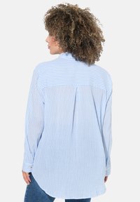 Hellblau-weiß gestreiftes Hemd mit langen Ärmeln, einem Rückenfalten, und Knopfdetails an den Manschetten. Weicher, strukturierter Stoff.