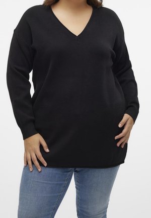 Pull noir à col en V avec des longues manches, fabriqué en matériau doux, présente une coupe décontractée et des fentes latérales pour faciliter les mouvements.