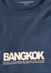 Marineblauw katoenen t-shirt met gedurfde witte tekst "BANGKOK" en namen van wijken. Ronde halslijn en gladde textuur. Maat large.